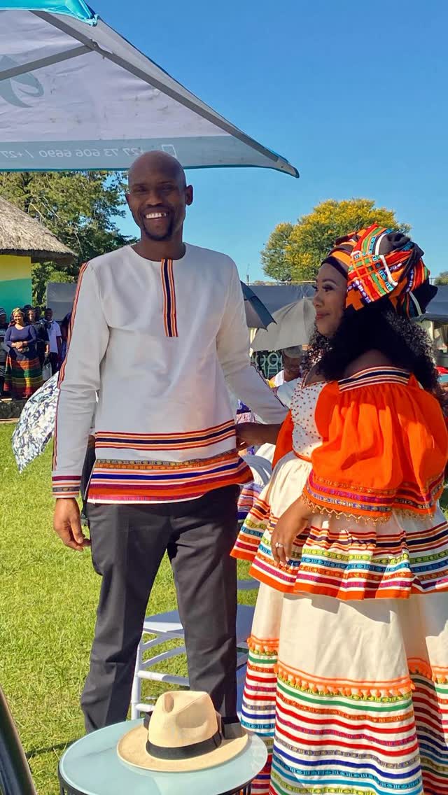Smiling couple in traditional attire under a branded tent